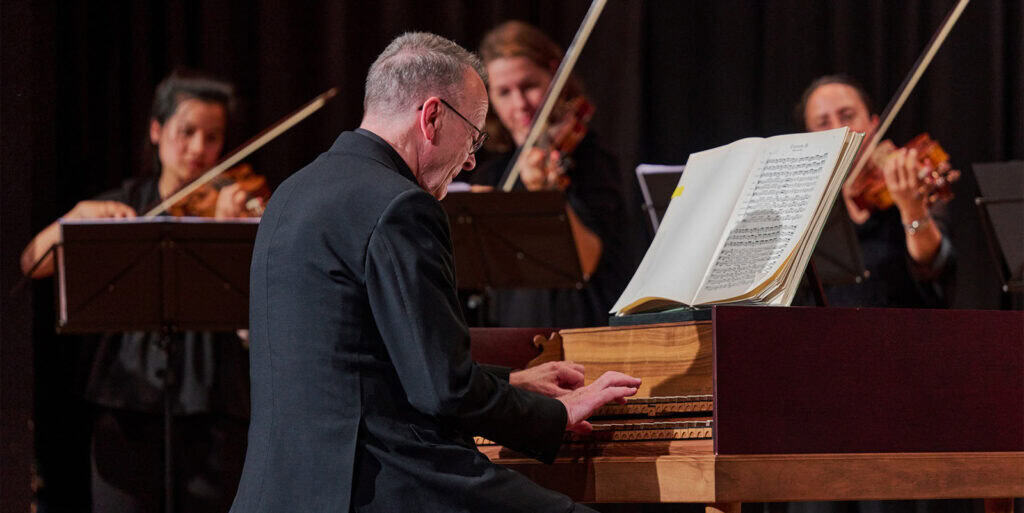 Ein Mann, der auf einem Klavier spielt, begleitet von einem Orchester