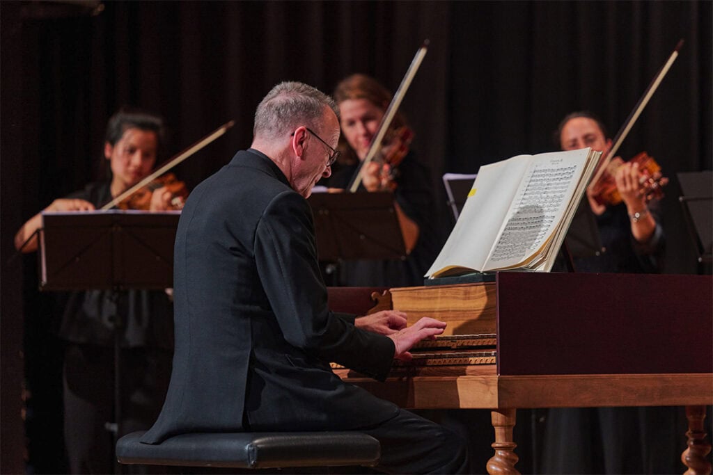 Ein Mann, der auf einem Klavier spielt, begleitet von einem Orchester